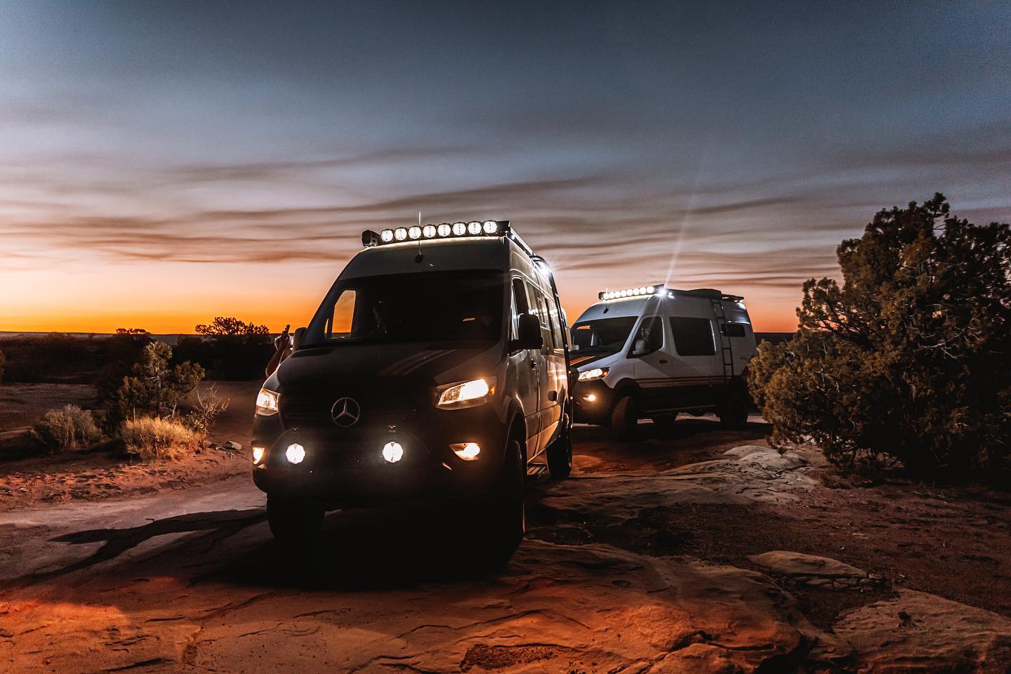 Two Best Mode 4x4 campervans drive through the night across the desert